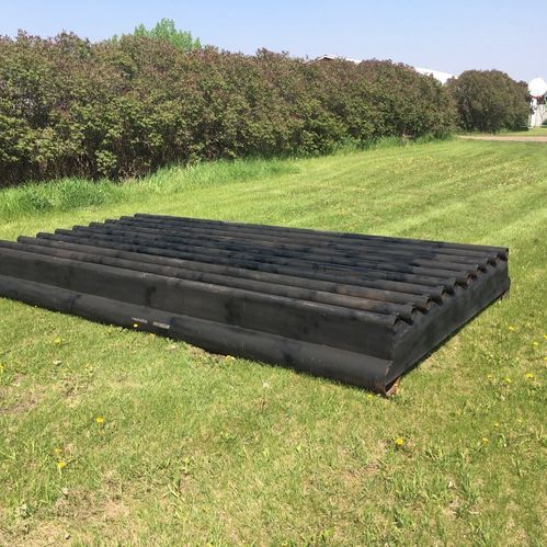 Image of metal cattle guard laying on a grass field