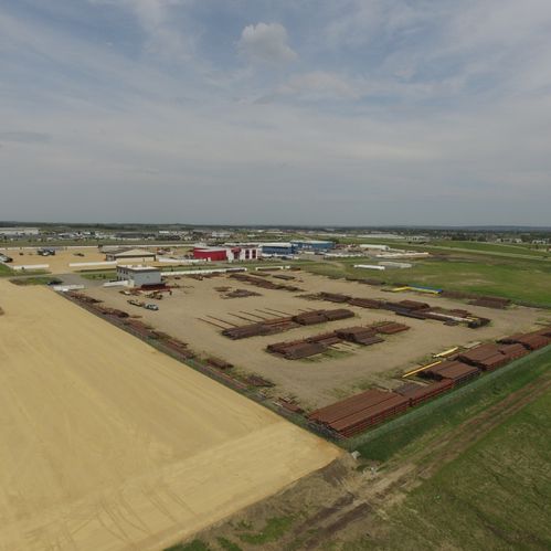 Bird's-eye view of an open field with metal objects laying on the ground and small buildings in the distance