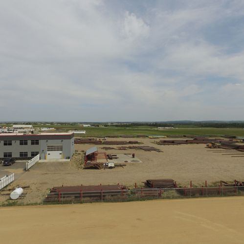  Bird's-eye view of a building and an open field with metal objects laying on the ground